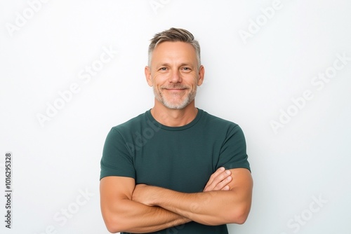 Happy middle aged man isolated on white studio background. Confident mature mid adult handsome male model wearing t-shirt looking at camera with arms crossed.