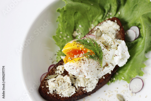 Breakfast. Poached Egg on Rye Bread Toast with Cream Cheese, Garnished with Pepper, Seeds, Dill, and Radish. 