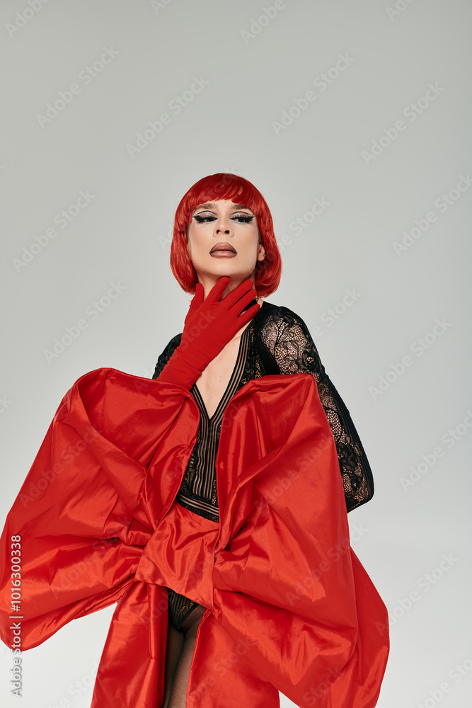 A striking drag queen showcases a bold red ensemble, exuding confidence and artistry.