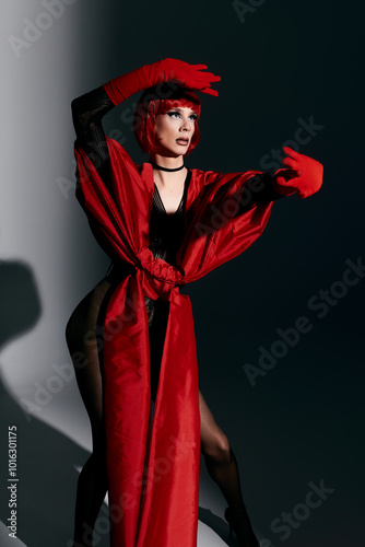 A stunning drag queen poses artfully in a bold red outfit, exuding charisma and flair.