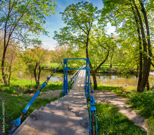 Empty pedestrian bridge over Seret river. Sunny spring view of Topilche park, Ternopil, Ukraine, Europe. Traveling concept background. photo