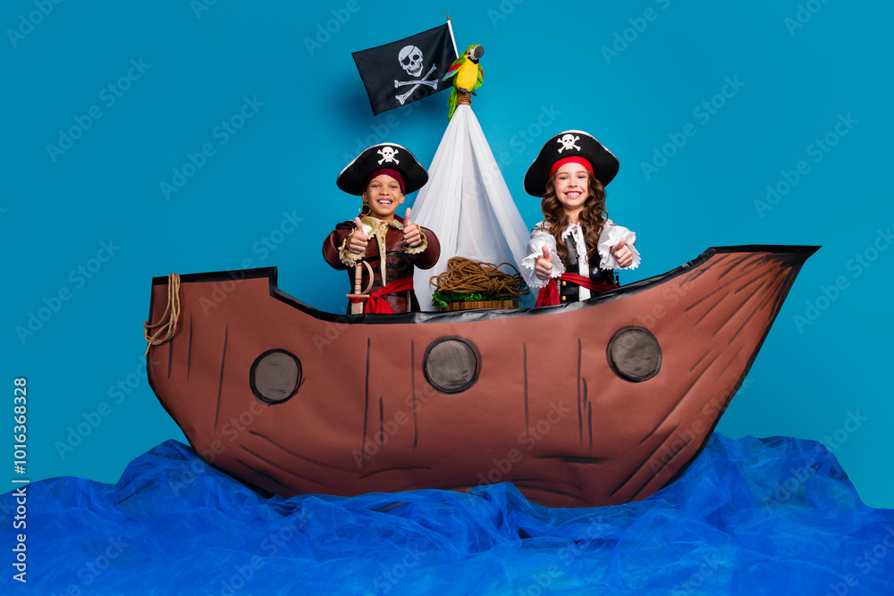 Full body photo of cute little boy girl show thumb up dressed pirates costumes float ship decor isolated on blue color background Full body photo of cute little boy girl show thumb up dressed pirates costumes float ship decor isolated on blue color background