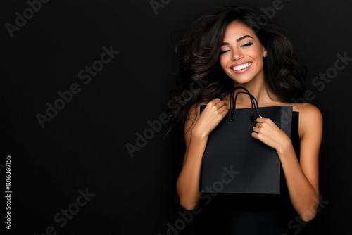 A woman is holding a black shopping bag and smiling