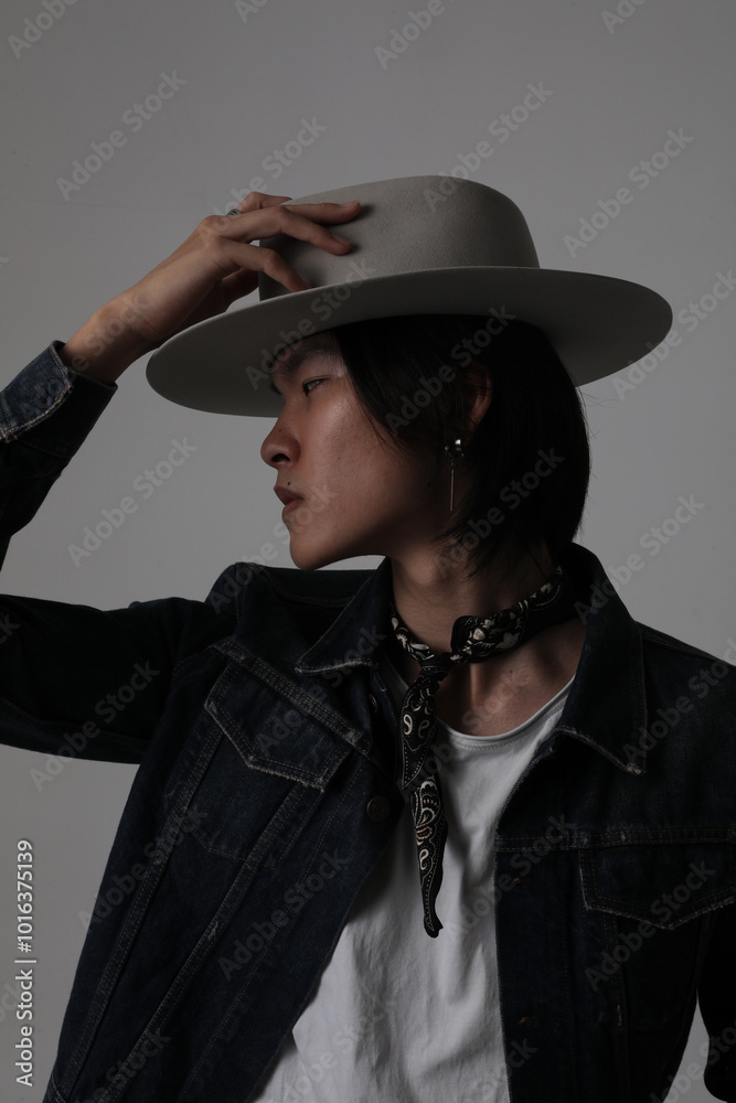 Fototapeta premium Stylish young man wearing hat posing indoor over white background. Vertical.
