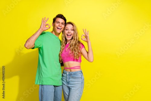 Photo of two nice young people show okey symbol empty space wear t-shirt isolated on bright yellow color background