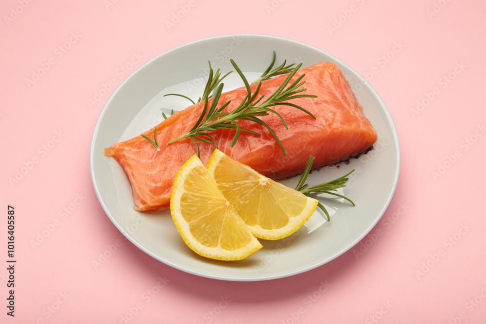 Red fish. Raw salmon fillet with rosemary and lemon on plate on pink background. Red fish. Raw salmon fillet with rosemary and lemon on plate on pink background.