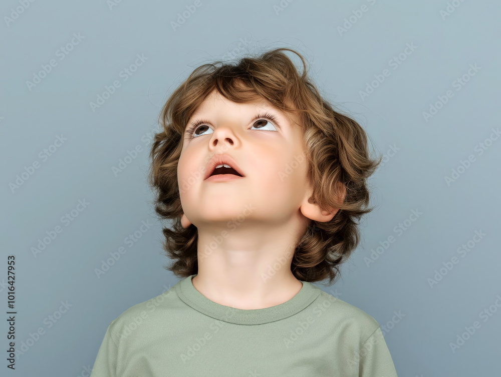 Young boy looking up in wonder, with a light blue background, representing curiosity and childhood innocence Young boy looking up in wonder, with a light blue background, representing curiosity and childhood innocence