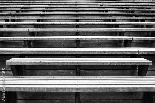 Rows of empty wooden bleachers in black and white, emphasizing minimalism and space.