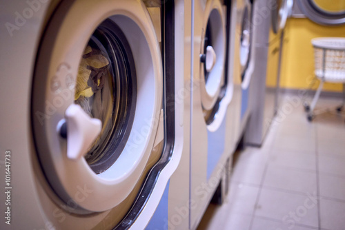 ф      young plus size  woman loads clothes into a washing machine in a laundry room in the basement of a student dormitory