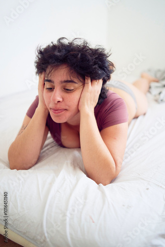  tired young plus size woman in home clothes on bed in student dormitory