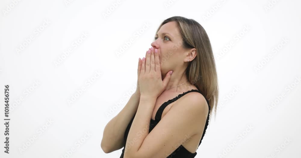 Young woman feels fear and covers mouth with trembling hands on white background. Female in open top hears loud noise and flinches slow motion Young woman feels fear and covers mouth with trembling hands on white background. Female in open top hears loud noise and flinches slow motion