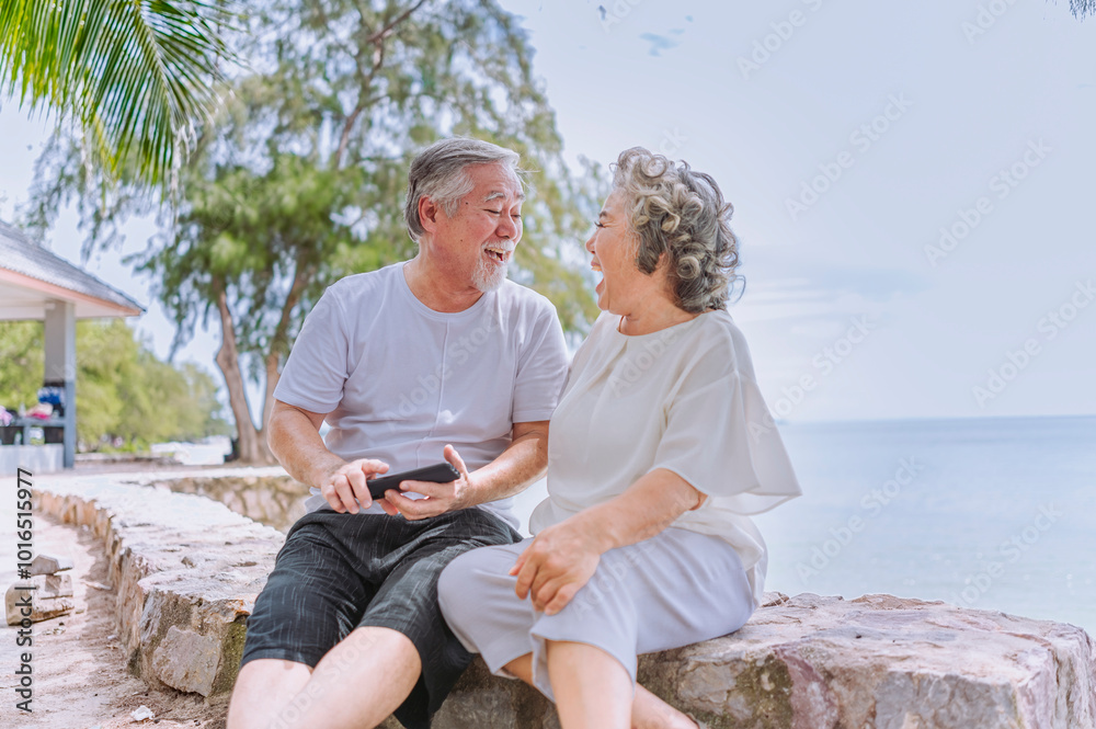 Happy and relax asian man and woman elder retired couple enjoying with smartphonein retired vacation at sea beach outdoor. Family outdoor lifestyle Happy and relax asian man and woman elder retired couple enjoying with smartphonein retired vacation at sea beach outdoor. Family outdoor lifestyle