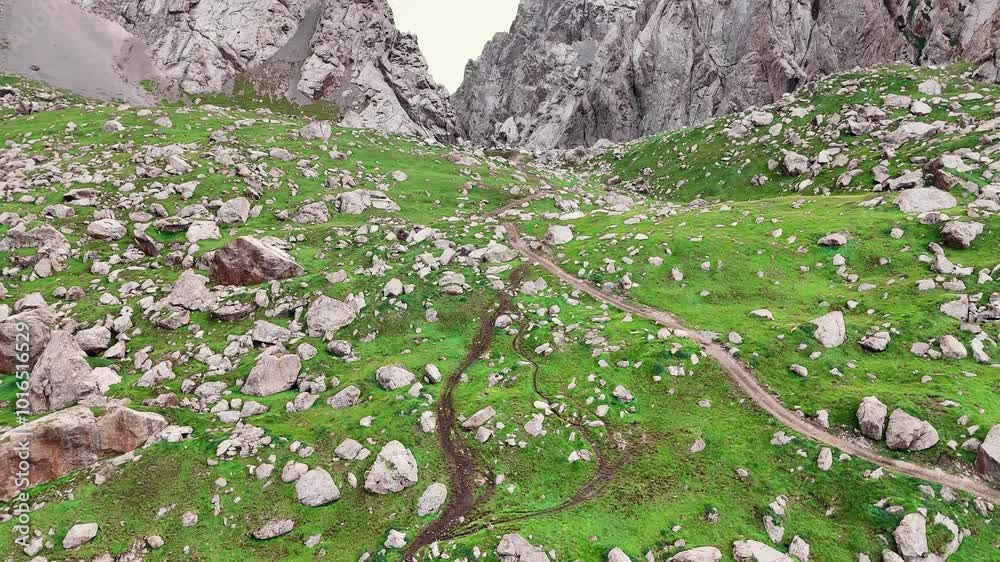 A fabulous mountain road runs through the green grass and huge rocks ...