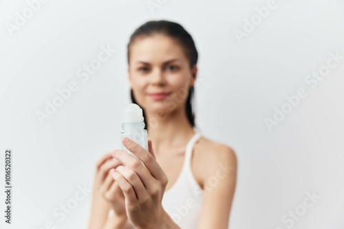 deodorant, skincare, beauty, hygiene, personal care, woman, healthy lifestyle, grooming, product, freshness, white background, soft colors, relaxation, self care A woman holding a roll on deodorant