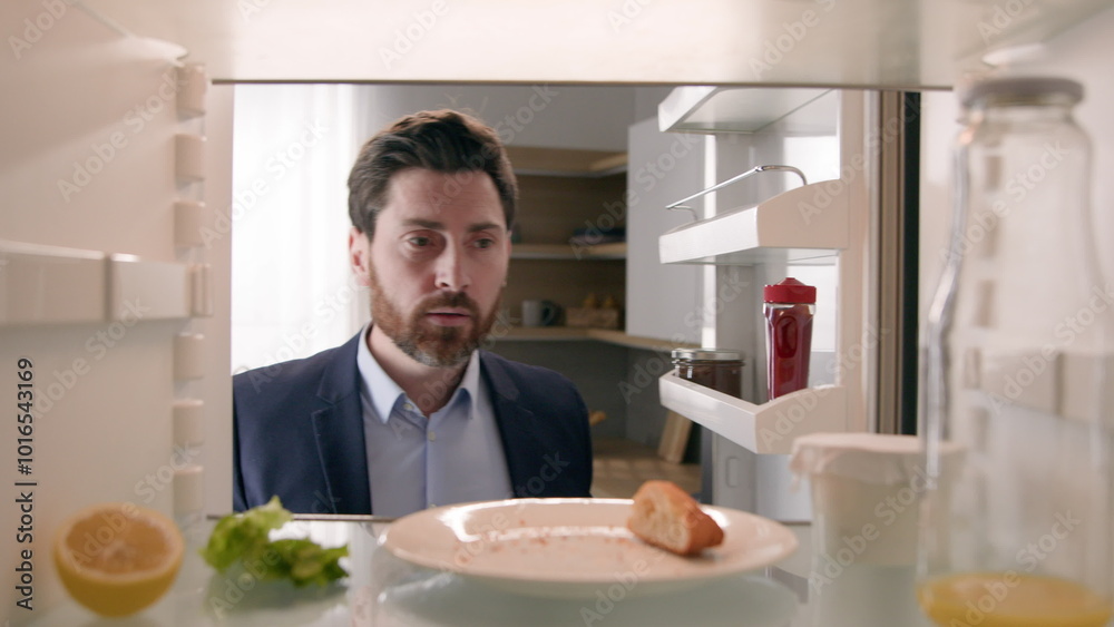 Hungry adult Caucasian businessman entrepreneur man after work open empty refrigerator with half lemon, lettuce leaf, bottle of milk and slice of bread eat crumbs POV point of view from inside fridge Hungry adult Caucasian businessman entrepreneur man after work open empty refrigerator with half lemon, lettuce leaf, bottle of milk and slice of bread eat crumbs POV point of view from inside fridge