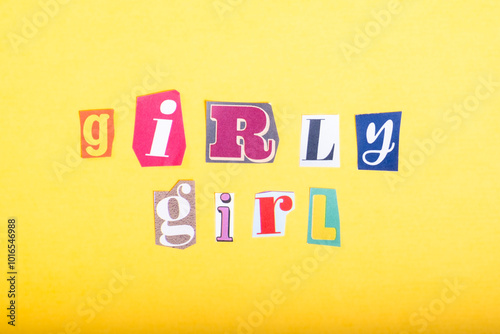 Phrase Girly Girl spelled in cut out newspaper style typography, isolated on yellow background.