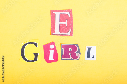 Phrase E Girl spelled in cut out newspaper style typography, isolated on yellow background.