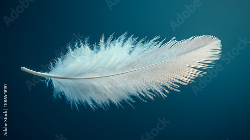 A serene image of a white feather gently floating in the air against a tranquil blue background, capturing a sense of peace and lightness. This visually soothing composition evokes feelings of calmnes photo