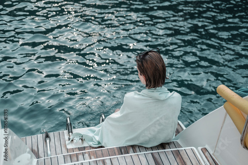 young woman sitting on back pupa of the sailing multihull boat, water background, yachting holiday concept photo