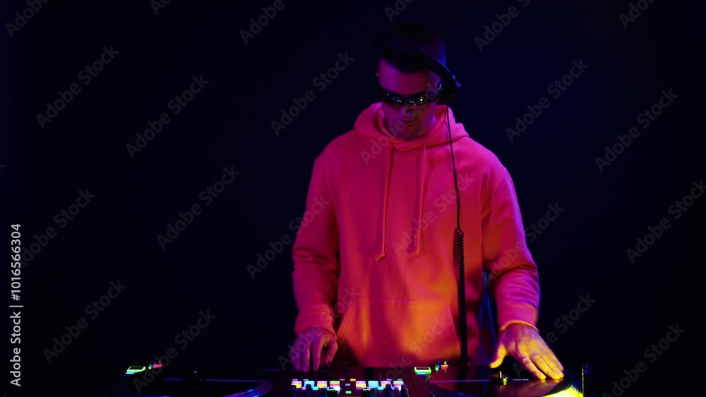 DJ performs live set with vibrant lighting in a dark studio, showcasing electronic music skills and engaging the audience