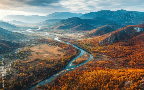 An aerial view of a valley with rivers winding through autumn forests, mountains looming in the background