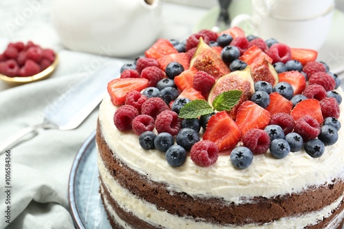 Delicious chocolate sponge cake with berries served on white table, closeup