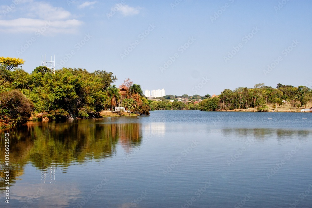 A photo of a still lake surrounded by green park landscape and the bustling city skyline in the background, taken during the golden hour. A photo of a still lake surrounded by green park landscape and the bustling city skyline in the background, taken during the golden hour.