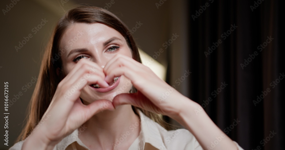 Young woman with dental braces showing heart shape with her hands. Concept of oral hygiene, dental care, and positive emotions. Close-up image highlighting orthodontic treatment. Young woman with dental braces showing heart shape with her hands. Concept of oral hygiene, dental care, and positive emotions. Close-up image highlighting orthodontic treatment.