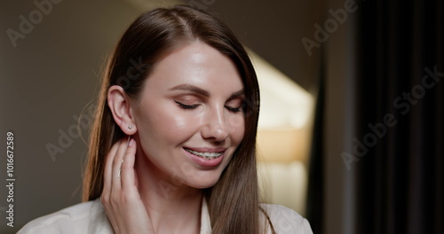 Dental Braces. Young woman with long hair smiling at home with dental braces. Close-up portrait showcasing orthodontic treatment and oral care. Girl with metal braces promoting dental hygiene.