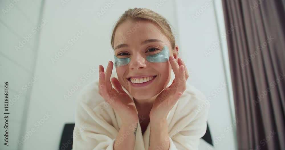 Smiling Woman Enjoying Her Skincare Routine with Cooling Eye Gel Patches, Wearing a White Bathrobe, Radiating Happiness and Self-Care Glow in a Bright Room Smiling Woman Enjoying Her Skincare Routine with Cooling Eye Gel Patches, Wearing a White Bathrobe, Radiating Happiness and Self-Care Glow in a Bright Room