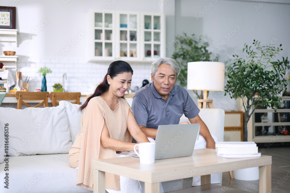 Asian senior woman and her husband are sitting on a sofa using laptop looking at life insurance plans and spending money. Asian senior woman and her husband are sitting on a sofa using laptop looking at life insurance plans and spending money.