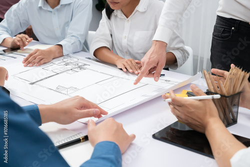 Diverse group of civil engineer and client working together on architectural project, reviewing construction plan and building blueprint at meeting table. Prudent