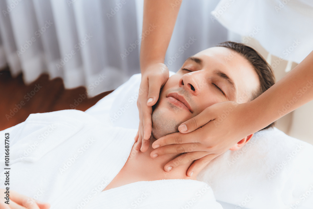 Caucasian man enjoying relaxing anti-stress head massage and pampering facial beauty skin recreation leisure in dayspa modern light ambient at luxury resort or hotel spa salon. Quiescent Caucasian man enjoying relaxing anti-stress head massage and pampering facial beauty skin recreation leisure in dayspa modern light ambient at luxury resort or hotel spa salon. Quiescent