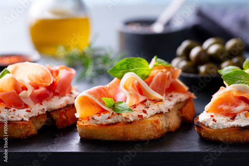 Tableau sur toile Bruschetta, crostini with Jam?n, ham and fresh basil on dark marble board