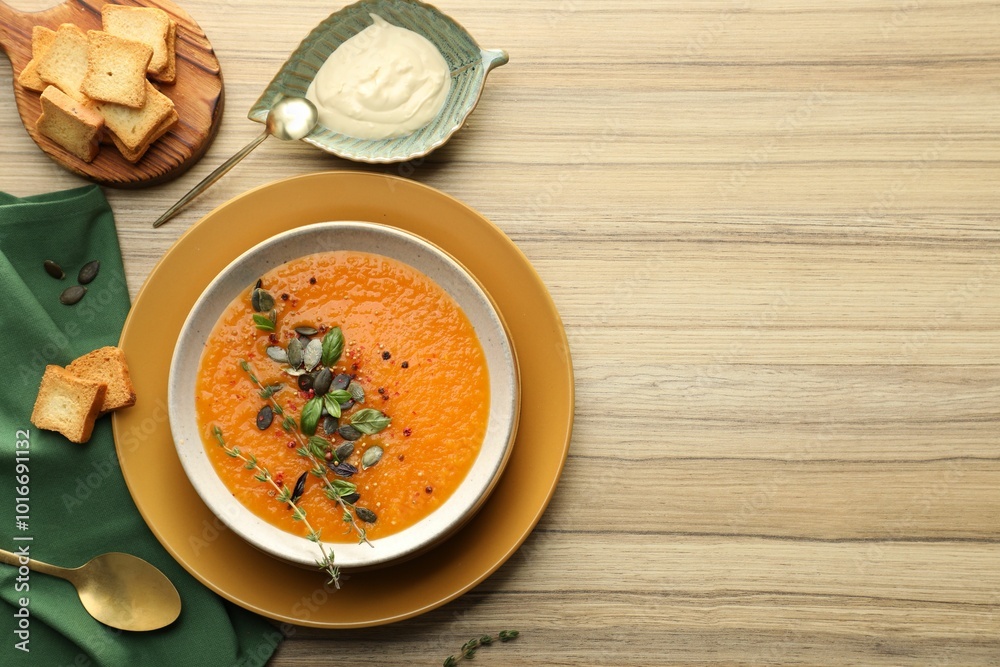 Delicious pumpkin soup with spices served on wooden table, flat lay. Space for text Delicious pumpkin soup with spices served on wooden table, flat lay. Space for text