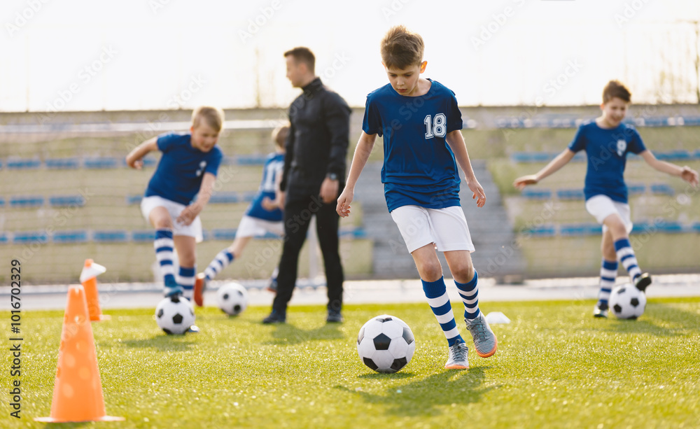 Teenagers on soccer training camp. The boys practice football on a grass pitch. Junior-level athletes improving soccer skills on outdoor training. Player jumping over hurdles and ladder-skipping Teenagers on soccer training camp. The boys practice football on a grass pitch. Junior-level athletes improving soccer skills on outdoor training. Player jumping over hurdles and ladder-skipping