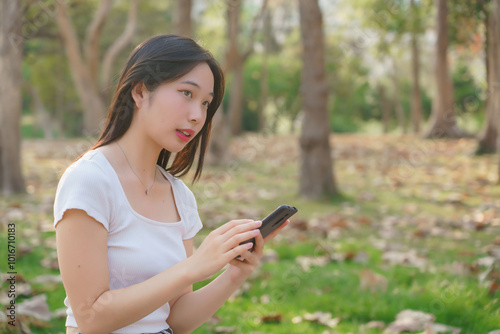 Young asian women sitting on bicycle to reading message chat and checking social media on smartphone after cycling bicycle in the park while relaxation with journey travel lifestyle for healthy