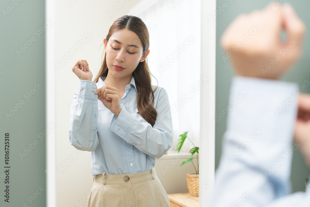 Get dress, asian young woman, businesswoman standing, hand buttoning up shirt formal, female getting dressed, ready before go to work looking reflection the mirror in bedroom in the morning at home. Get dress, asian young woman, businesswoman standing, hand buttoning up shirt formal, female getting dressed, ready before go to work looking reflection the mirror in bedroom in the morning at home.
