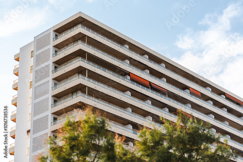 High-rise residential apartment building with multiple balconies in urban area, showcasing contemporary architectural design.