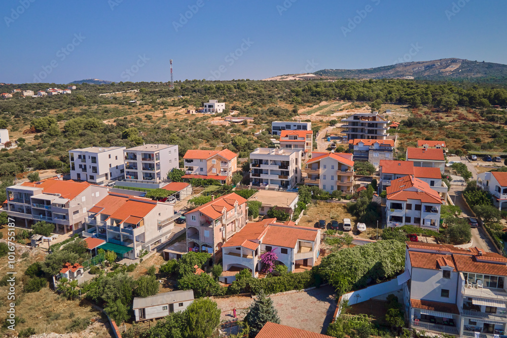 Aerial view of residential neighborhood with red roofed houses at summer day. Small coastal town with colorful buildings in Croatia Aerial view of residential neighborhood with red roofed houses at summer day. Small coastal town with colorful buildings in Croatia