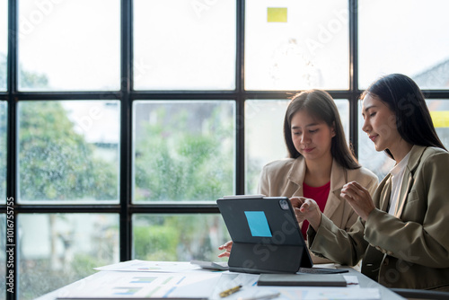 Two businesswomen having a meeting and working together using a tablet