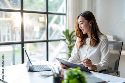 Asian businesswoman working with documents and using tablet in office