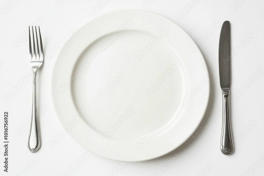 Empty white plate with fork and knife lying on a table Empty white plate with fork and knife lying on a table