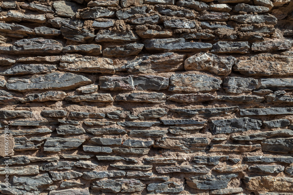 Old ruined masonry made of gray natural stone of different sizes and shapes. Background for design. Old ruined masonry made of gray natural stone of different sizes and shapes. Background for design.