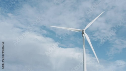 A wind turbine is standing tall in the sky above a cloudy day