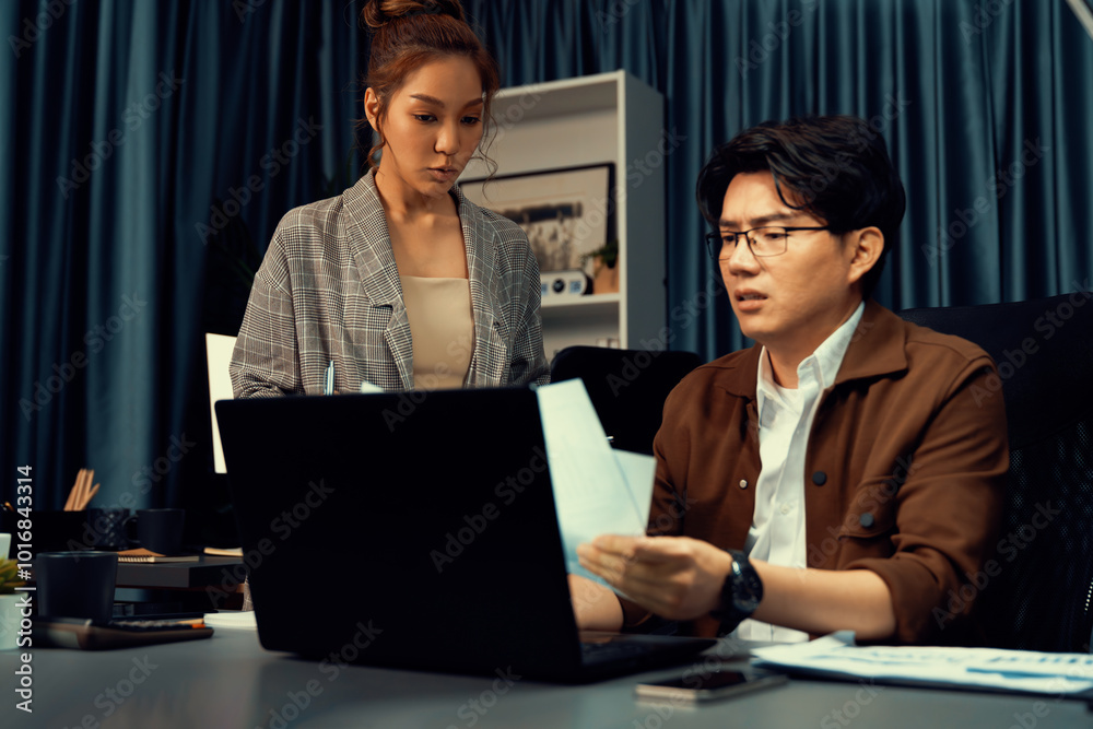 Obraz premium Managers discussing on document paperwork together for business planning on market share data at over late night time at modern home office, working on startup company deadline project job. Infobahn.