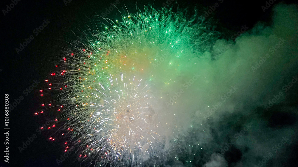 Fototapeta premium A vibrant display of green and red fireworks illuminates the night sky, symbolizing celebration and joy during New Year's Eve