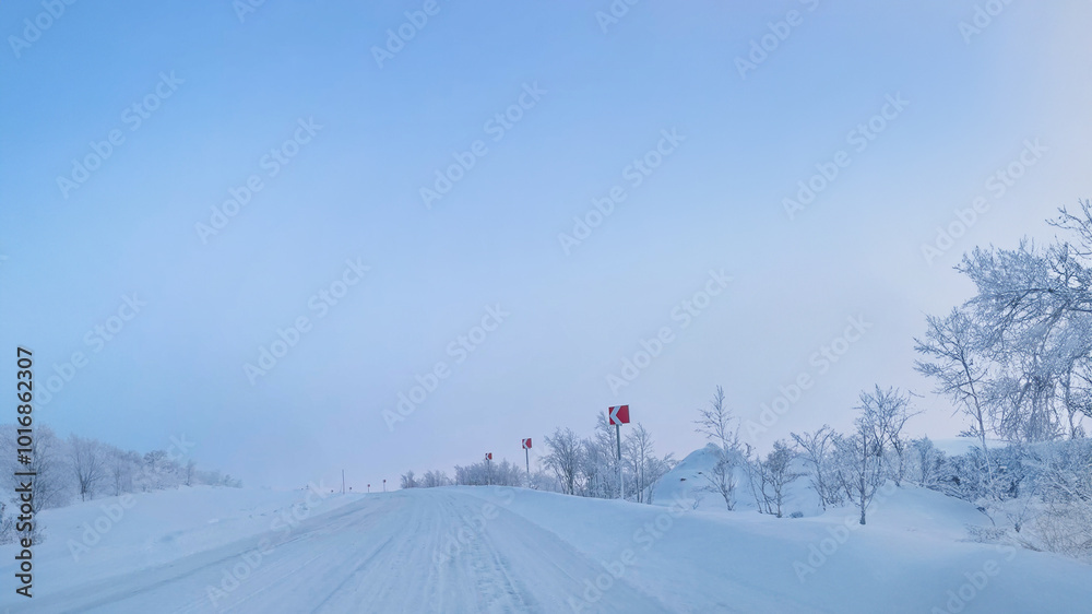 A snow-covered road under a clear blue sky, depicting winter travel challenges, perfect for Christmas-themed contexts A snow-covered road under a clear blue sky, depicting winter travel challenges, perfect for Christmas-themed contexts