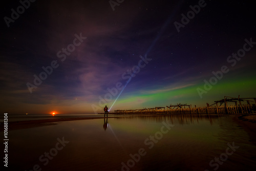 Man with a torch watching northern lights over the Sventoji old pier (Sventosios senasis molas), Sventoji, Palanga, Lithuania photo