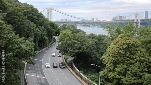 cars driving on the henry hudson parkway (west side of manhattan river) with george washington bridge gwb in the background at sunset  photo